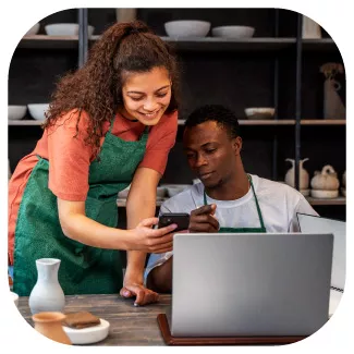 Jeune couple d'artisan travaillant sur un ordinateur et sur un smartphone